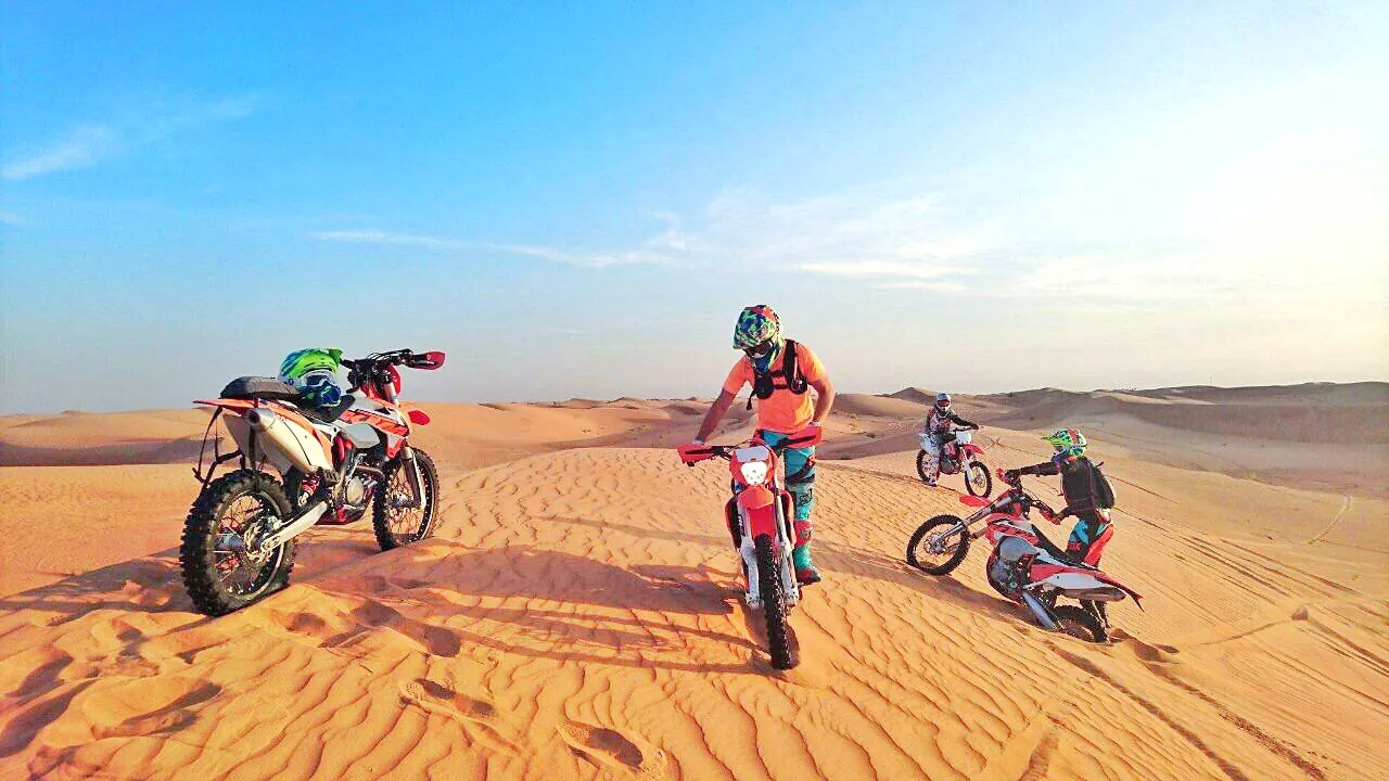 Motociclisti da motocross su una pista di sabbia al tramonto